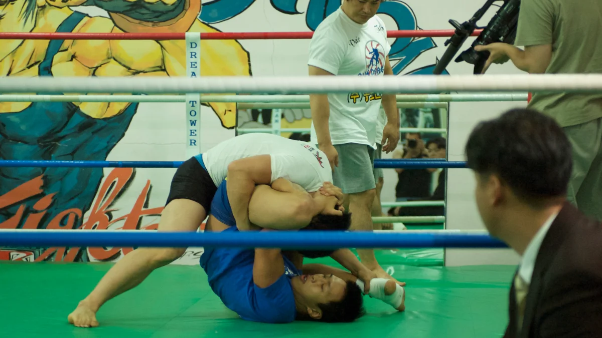 two people playing no-gi jiu-jitsu in a ring while being filmed